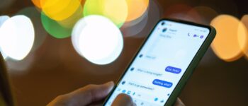 Person messaging on smartphone at night with bokeh lights.